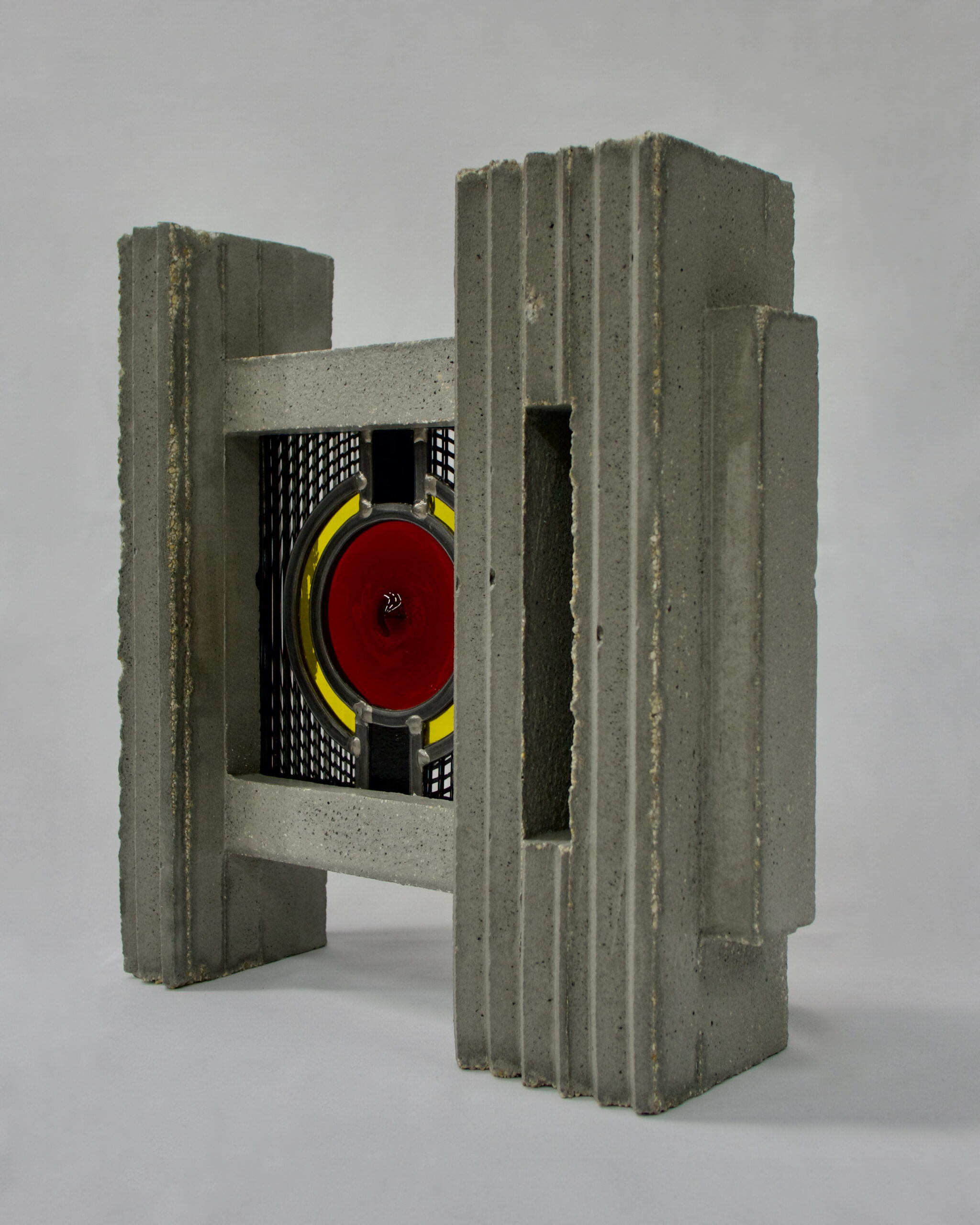 Sculpture en béton brut avec un vitrail rouge au cœur de cette pièce de l’atelier Anh